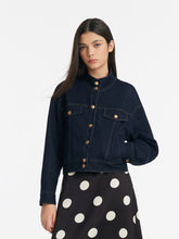 A lady wears a denim crop jacket and a dress.